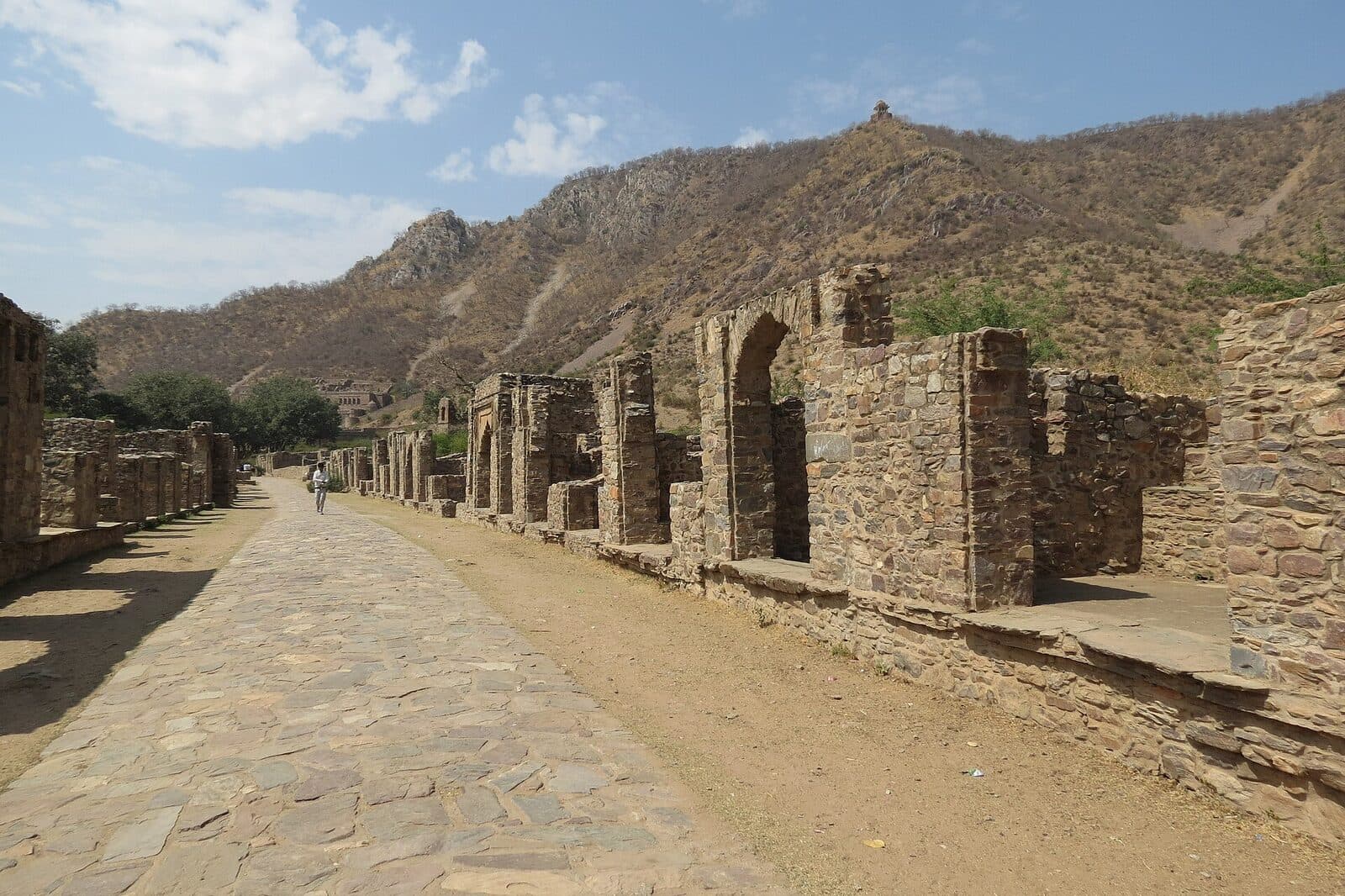 The ruined market street of Bhangarh beneath the Aravalli hills